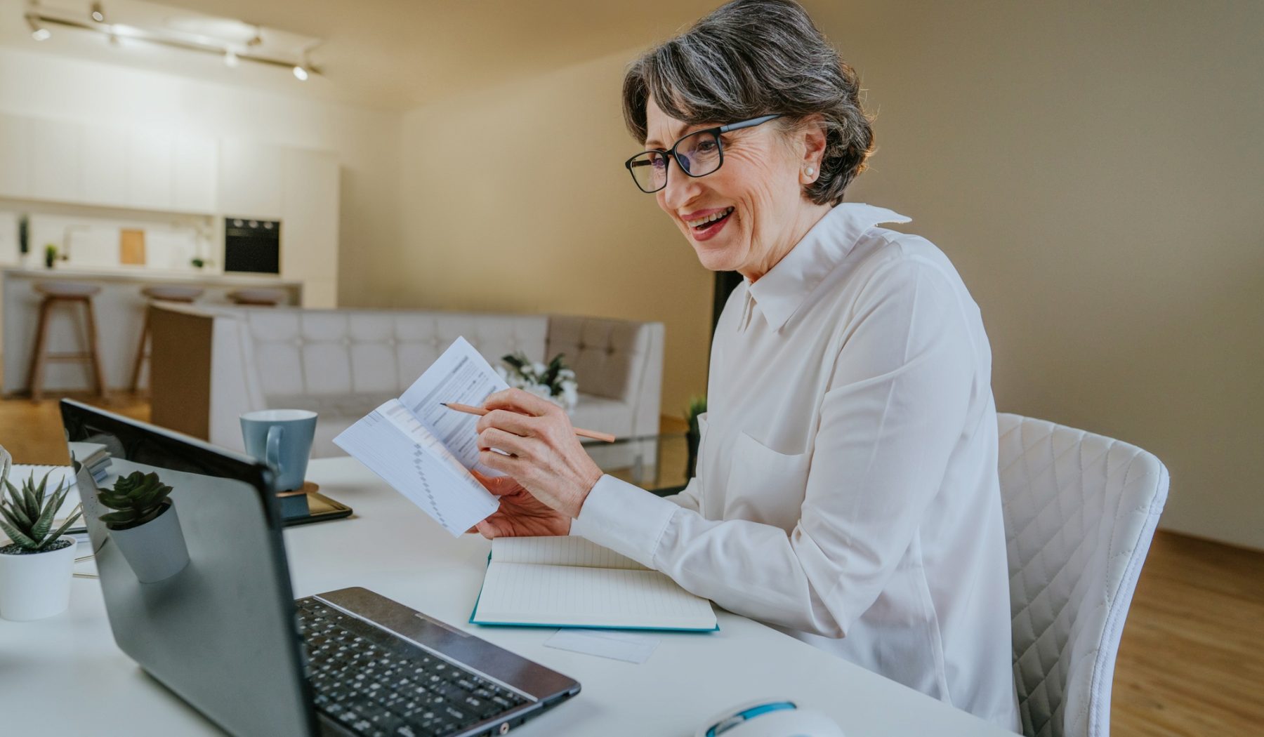 Portrait of happy mature woman learning foreign language using a laptop at home.